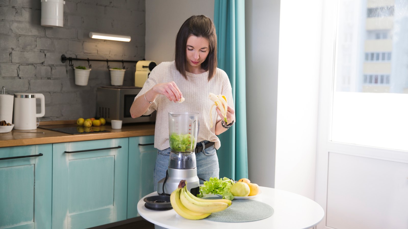 a young woman makes a smoothie in the kitchen in the morning. healthy nutrition, vegetarianism