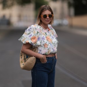 Aline Kaplan wearing Baum & Pferdgarten wide leg blue denim pants, & other stories white flower pattern cropped blouse and orange summer heels and Mango orange black shades on June 06, 2023 in Berlin, Germany.